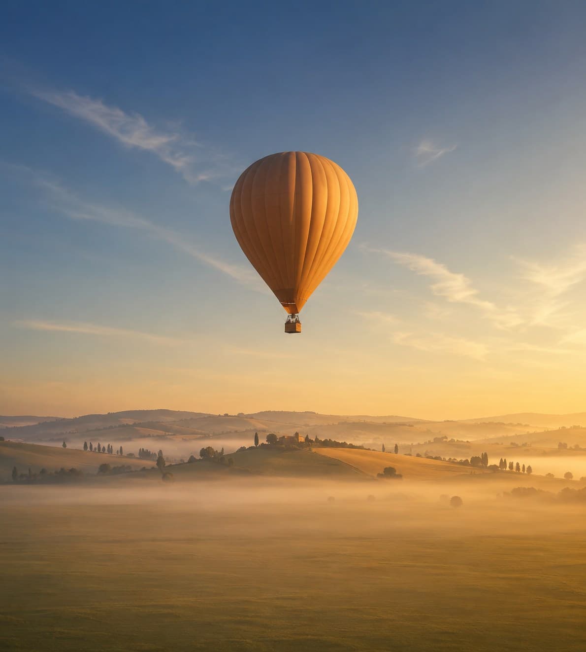 Montgolfière au-dessus de collines dans la brume, au lever du soleil